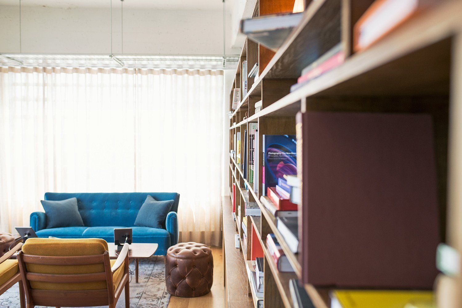 Ein Wohnzimmer mit einem blauen Sofa, Stühlen und Regalen voller Bücher.