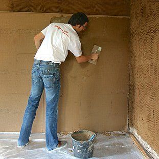 Ein Mann im weißen Hemd verputzt eine Wand