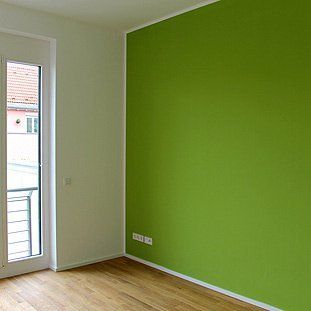 Ein leerer Raum mit grünen Wänden und einem großen Fenster.