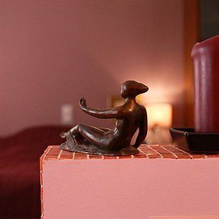 Eine Frauenstatue sitzt auf einer rosa Schachtel.