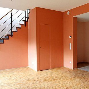 Ein leerer Raum mit orangefarbenen Wänden und einer Treppe