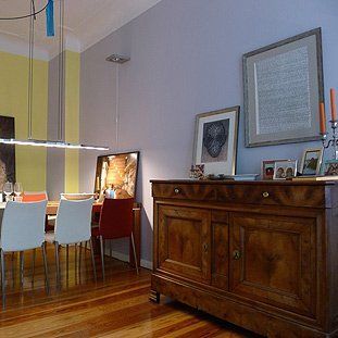 Ein Esszimmer mit Tisch und Stühlen und einer Holzkommode