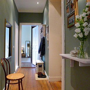 Ein Flur mit einem Stuhl und einer Vase mit Blumen