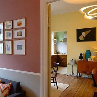 Ein Wohnzimmer mit Sofa, Sessel, Tisch und Bildern an der Wand.