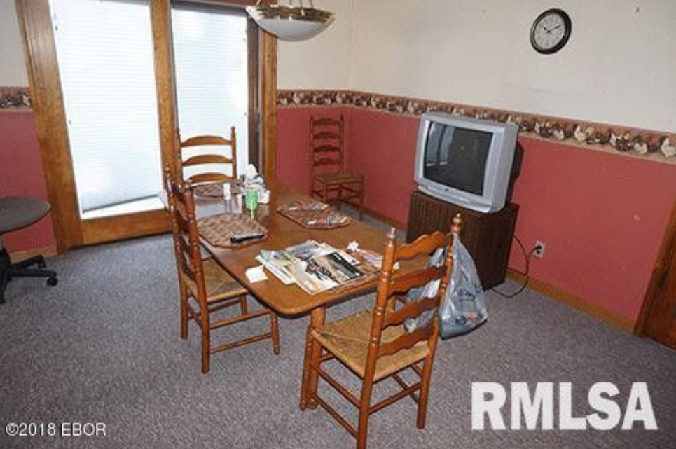 A dining room with a table and chairs and a television.