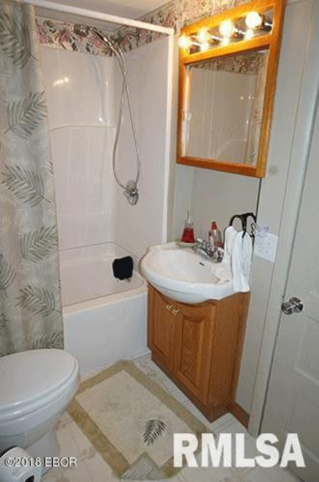 A bathroom with a sink toilet and shower with rmlsa written on the bottom
