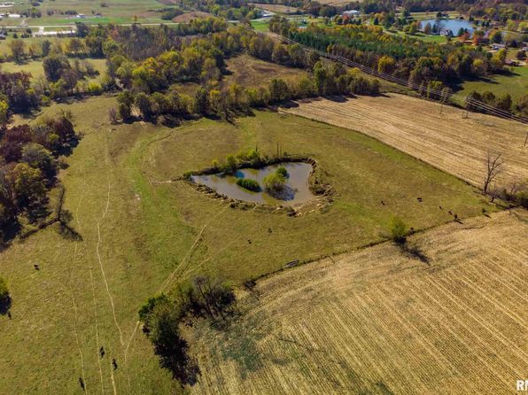 An aerial view of a field with a pond in the middle of it.