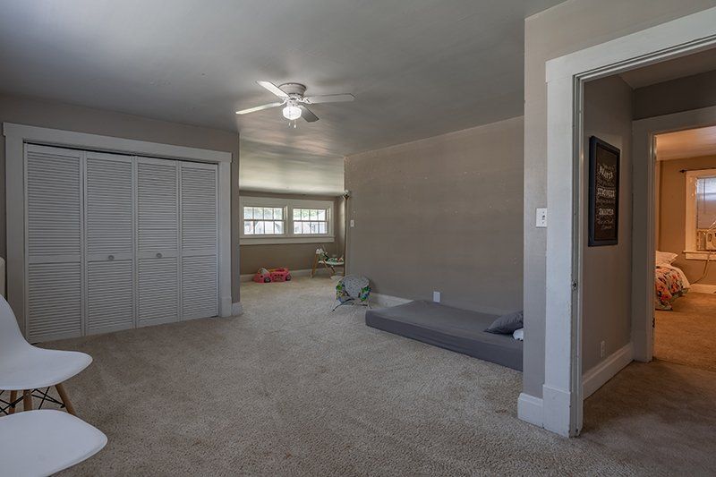 A living room with a mattress on the floor and a ceiling fan.