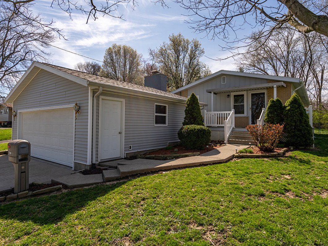 A small white house with a garage and a porch.