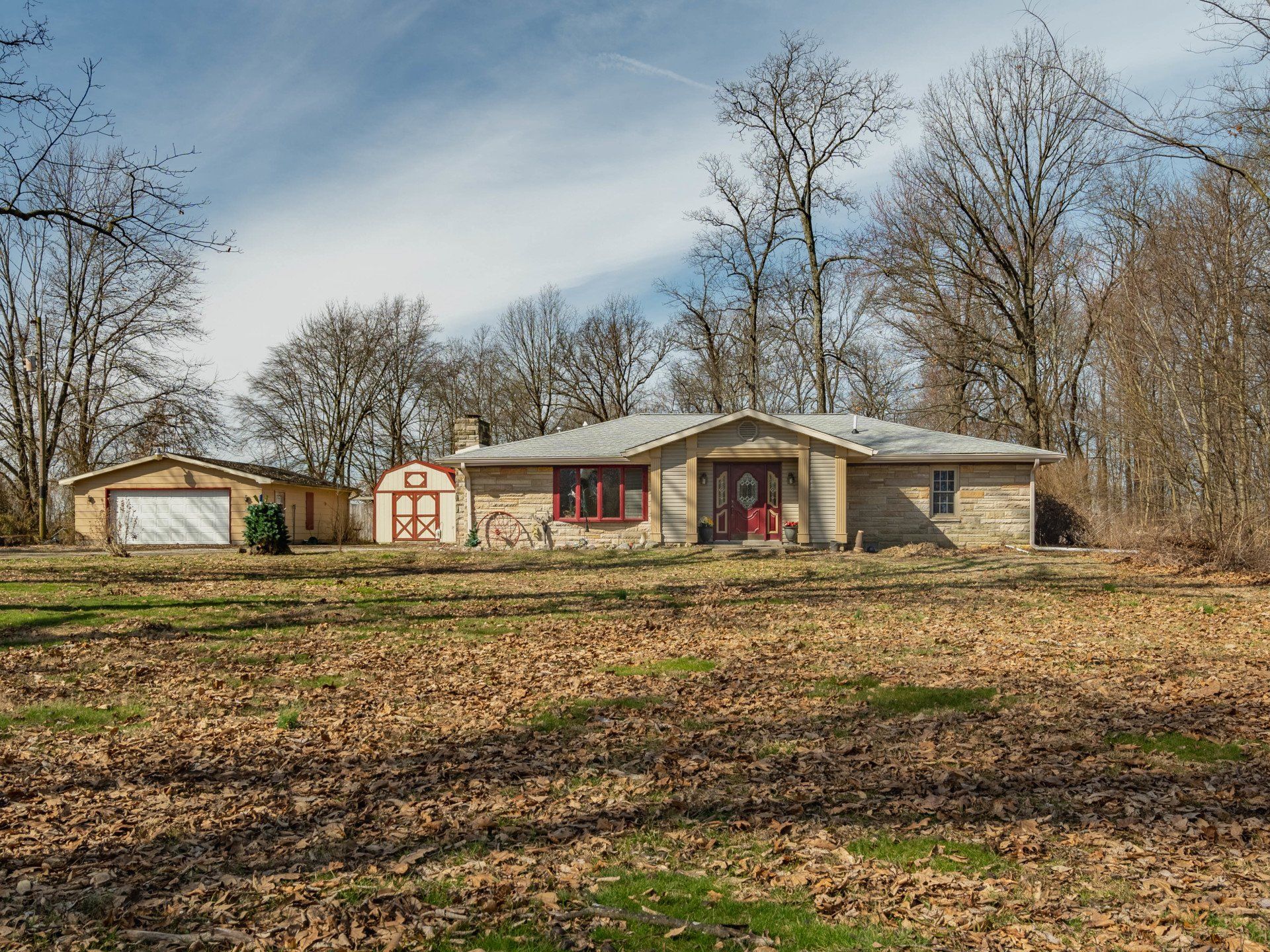A house is sitting in the middle of a field surrounded by trees.