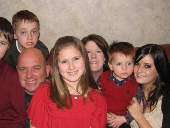 A group of people posing for a picture including a girl in a red shirt