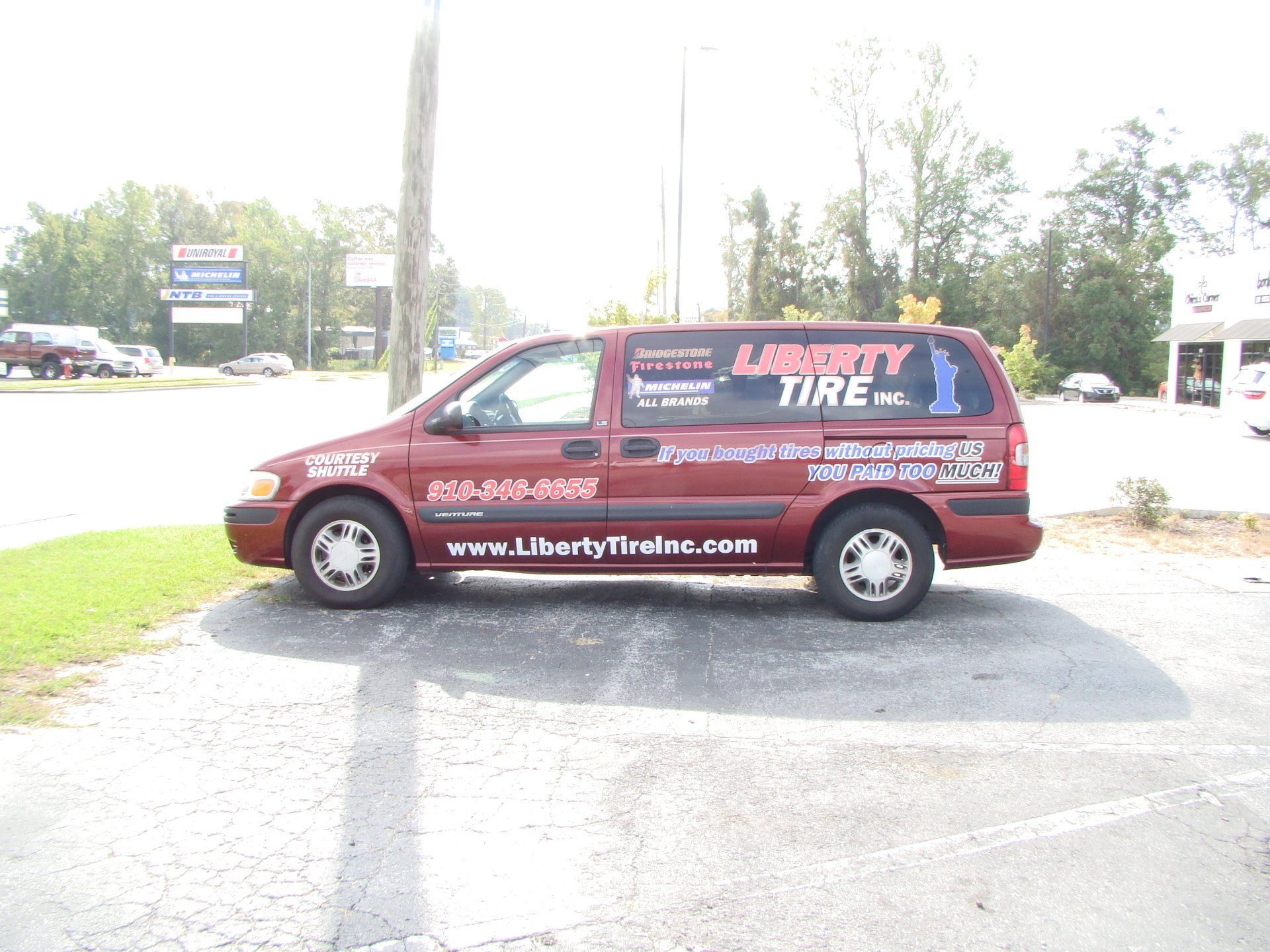 Red Liberty Tire service van parked by roadside with company website on the side