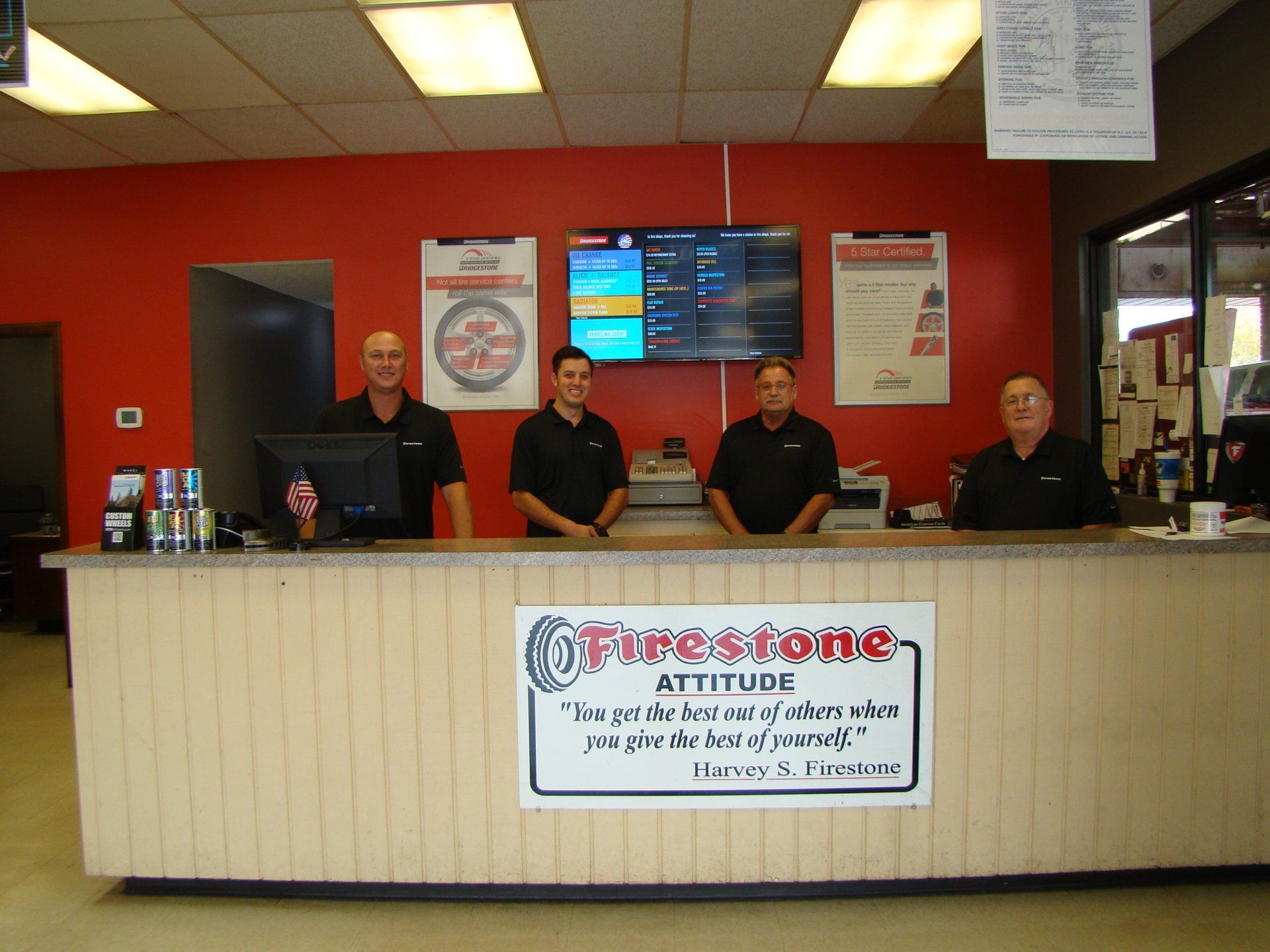 Four staff behind a front desk in a red-walled office lobby with a sign reading “Expressions”
