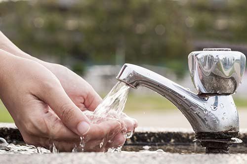 person washing hands under faucet after installing septic tanks in Benedict, NE