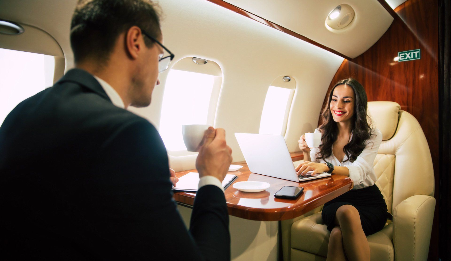 A man and a woman are sitting at a table on an airplane.