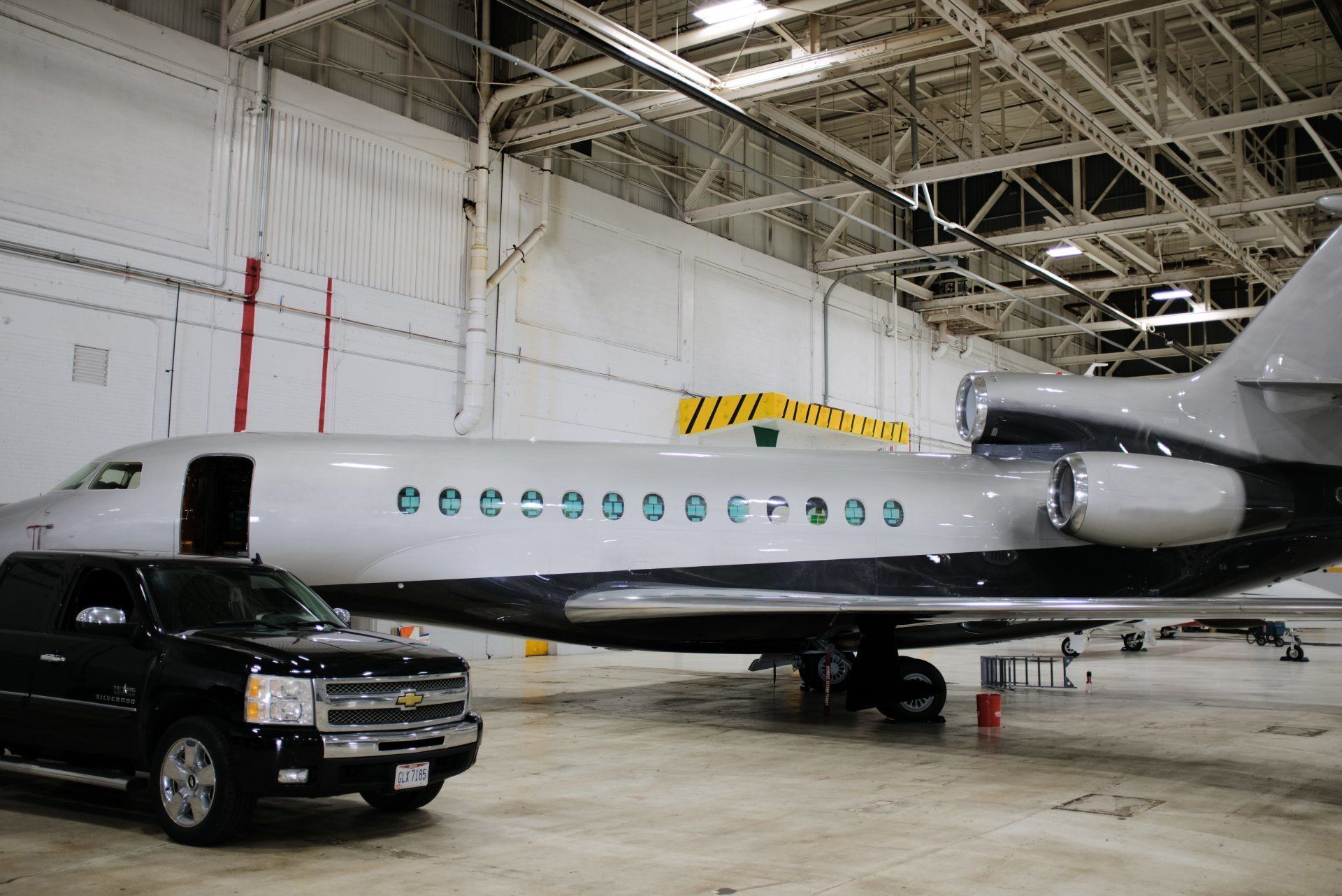 A private jet is parked in a hangar next to a black suv