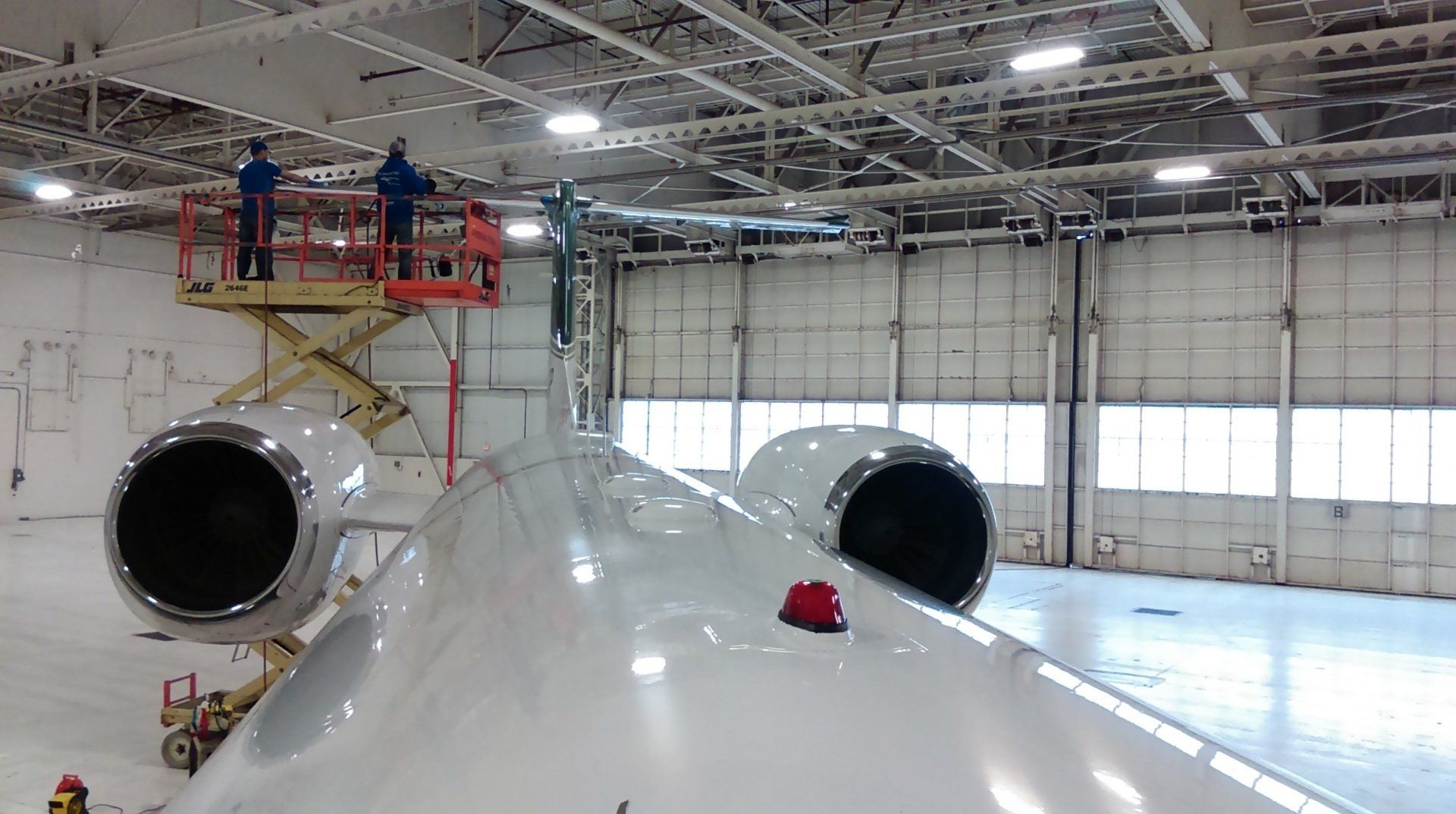Two men are working on a plane in a hangar
