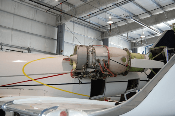 A large engine is sitting on the side of a plane in a hangar.