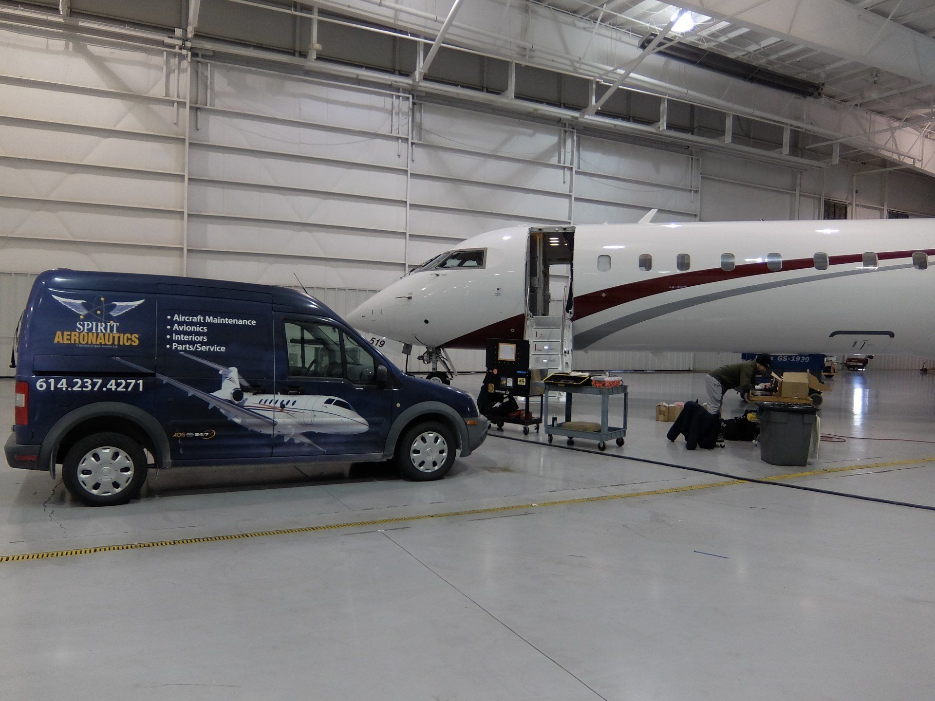 A van is parked next to an airplane in a hangar