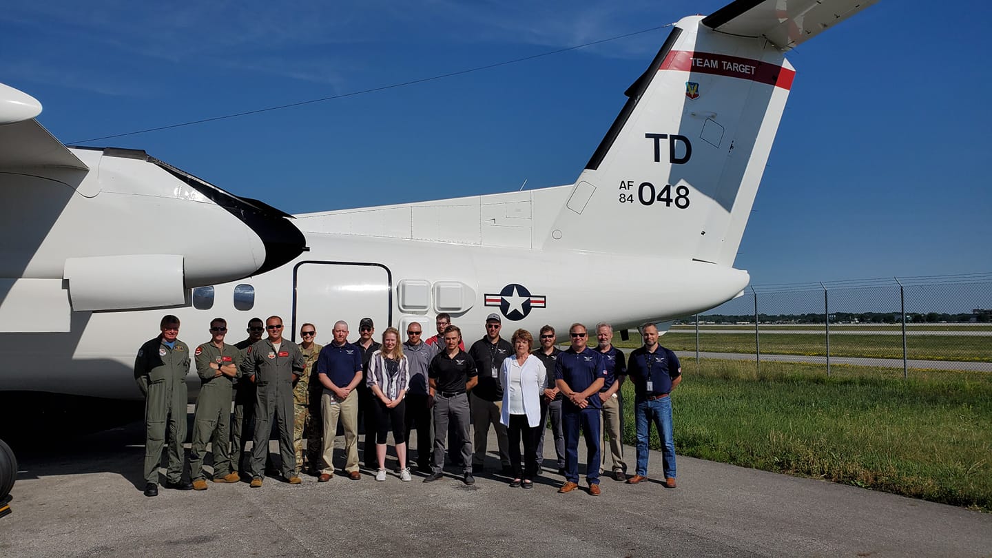 A group of people standing in front of a plane that says td 043