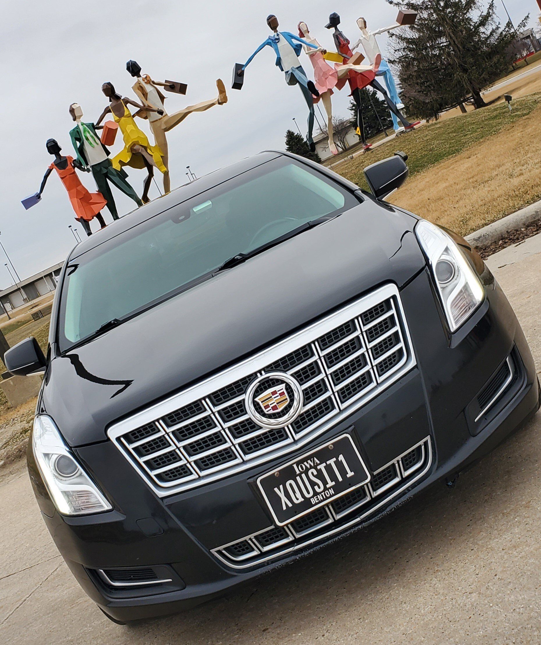 A black limo parked in front of statues at the Cedar Rapids Eastern Iowa Airport.