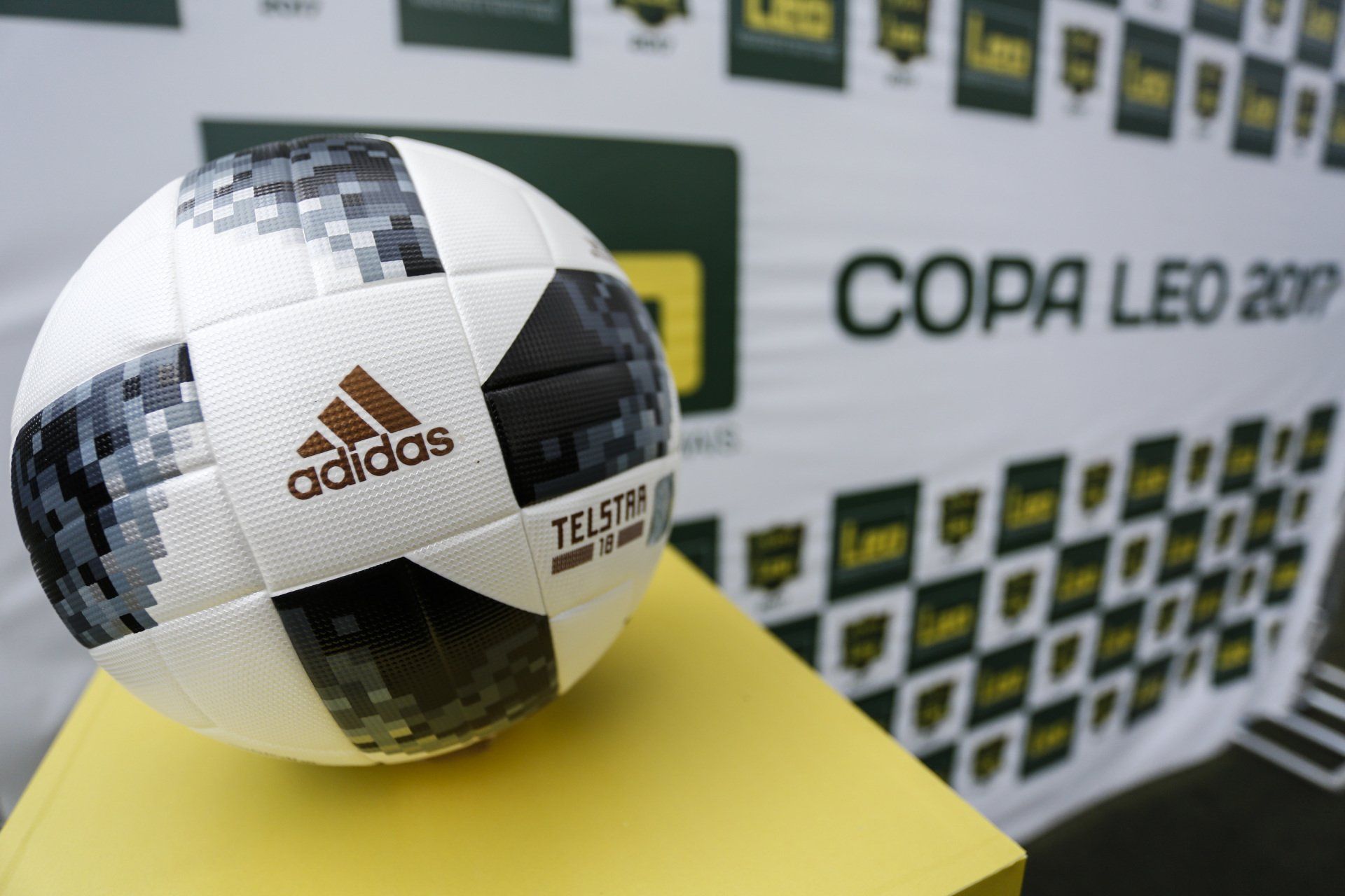 Bola de futebol em um suporte amarelo com a faixa 