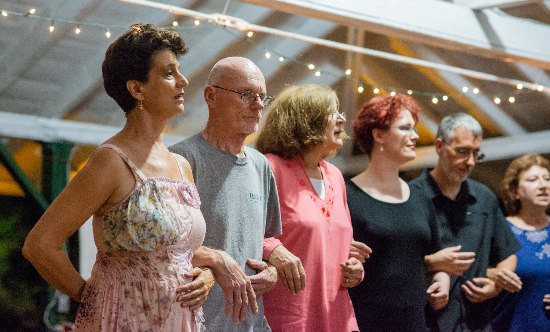 A group of people are standing next to each other holding hands.