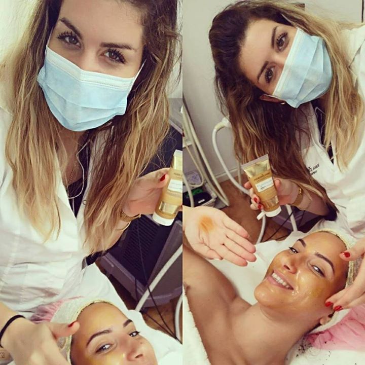 Two masked estheticians giving a facial treatment to a reclining client in a spa room