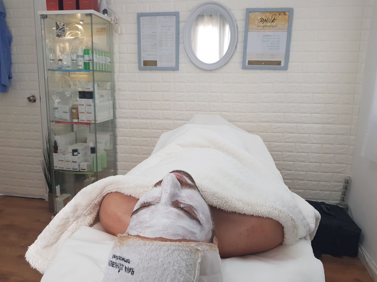 Person lying face down on a massage table with a towel, in a spa treatment room.