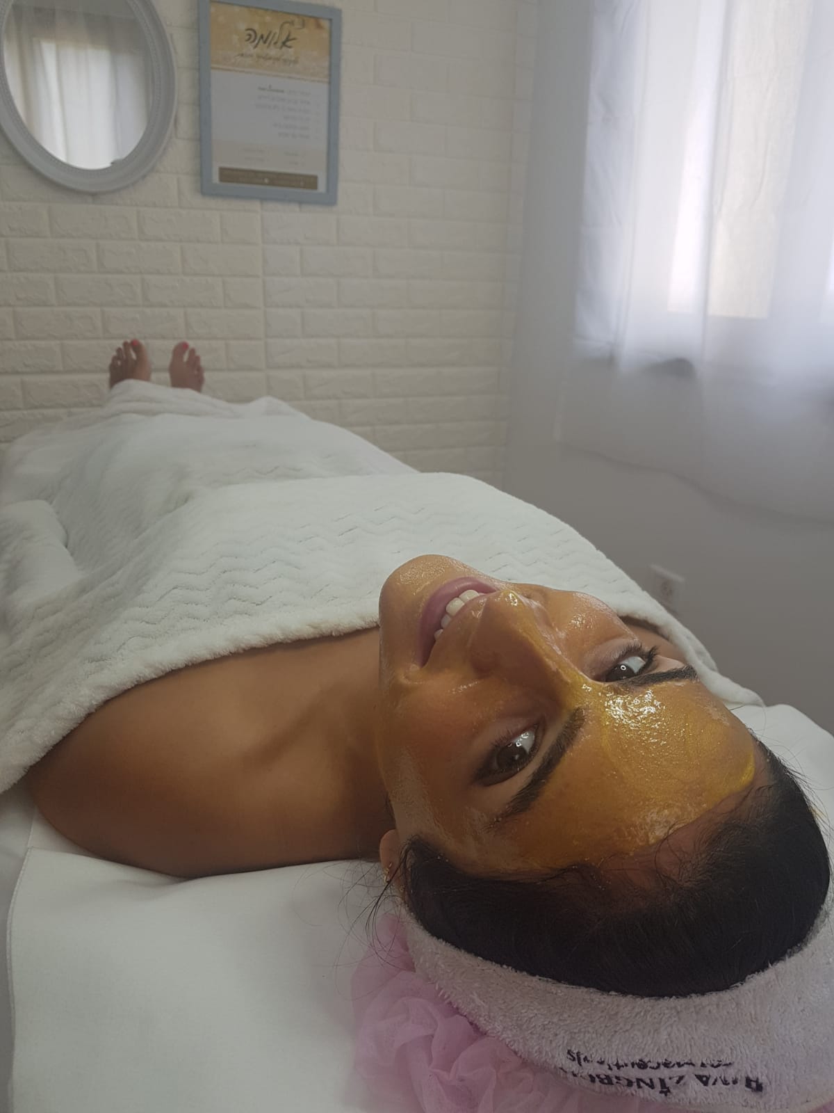Person lying on a massage table with a white towel, in a bright spa room.