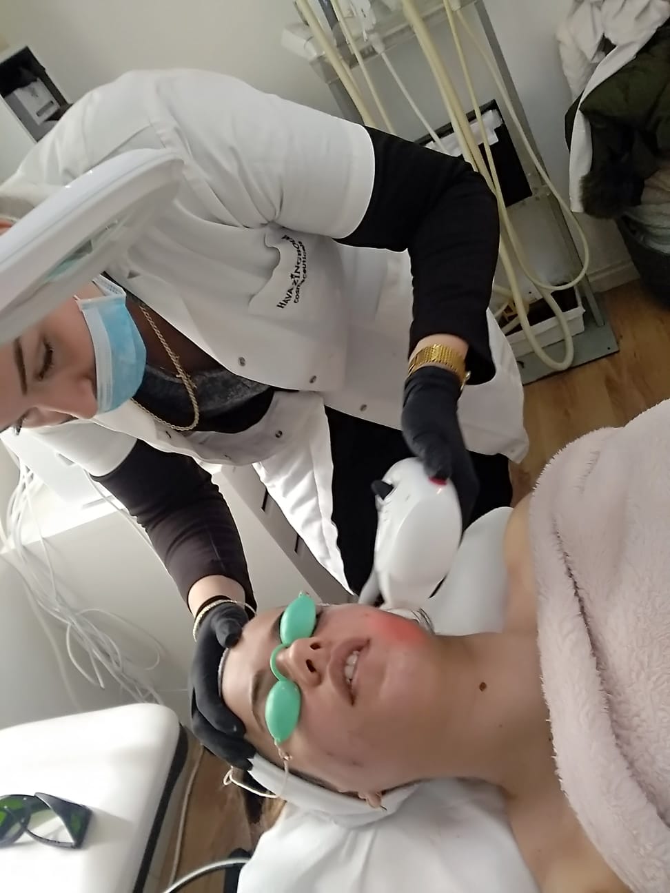 Clinician examining a patient with green eye shields in a treatment room