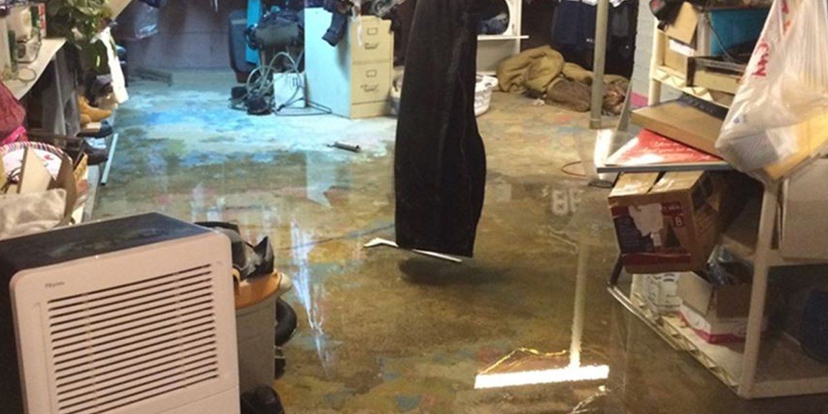 A flooded basement with a vacuum cleaner and a humidifier.