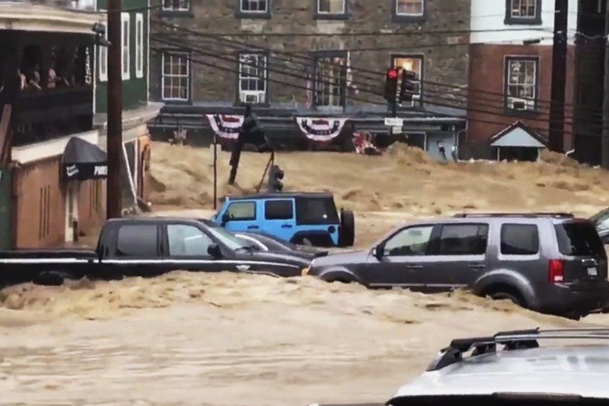 A flooded street with cars parked in front of a building.