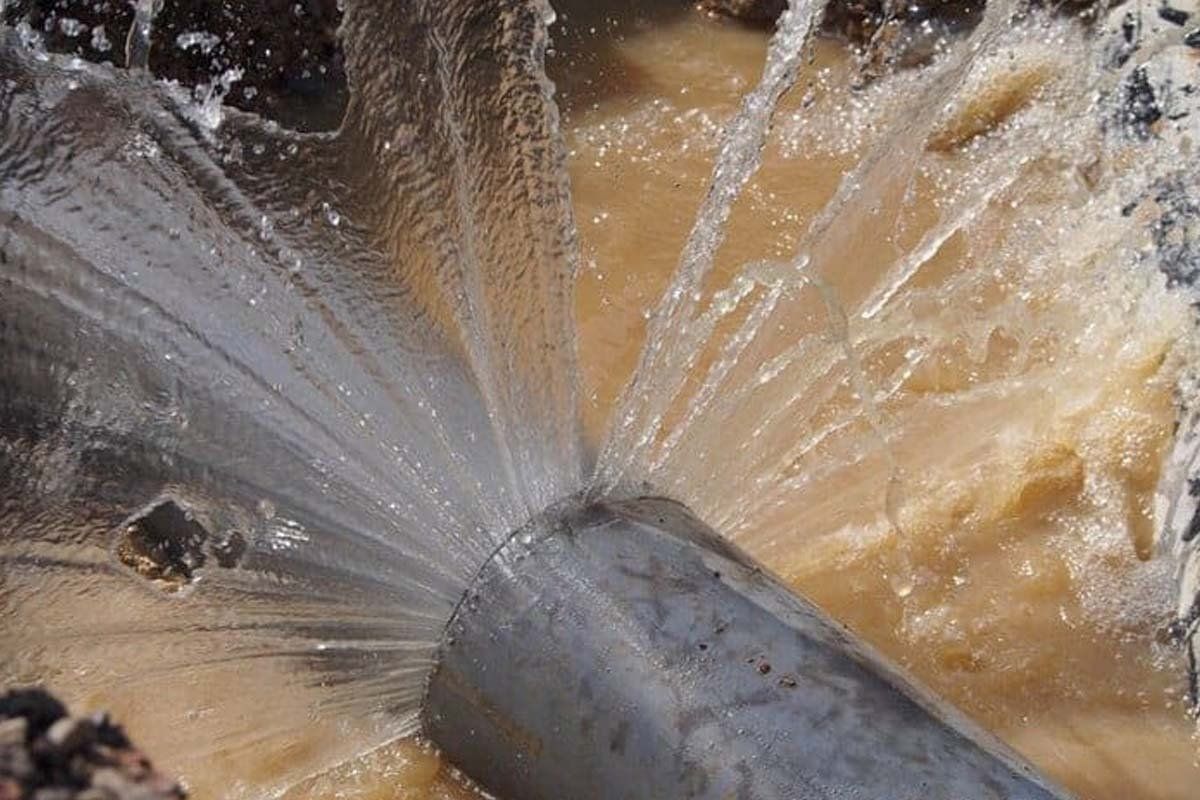 A pipe is leaking water into a puddle.