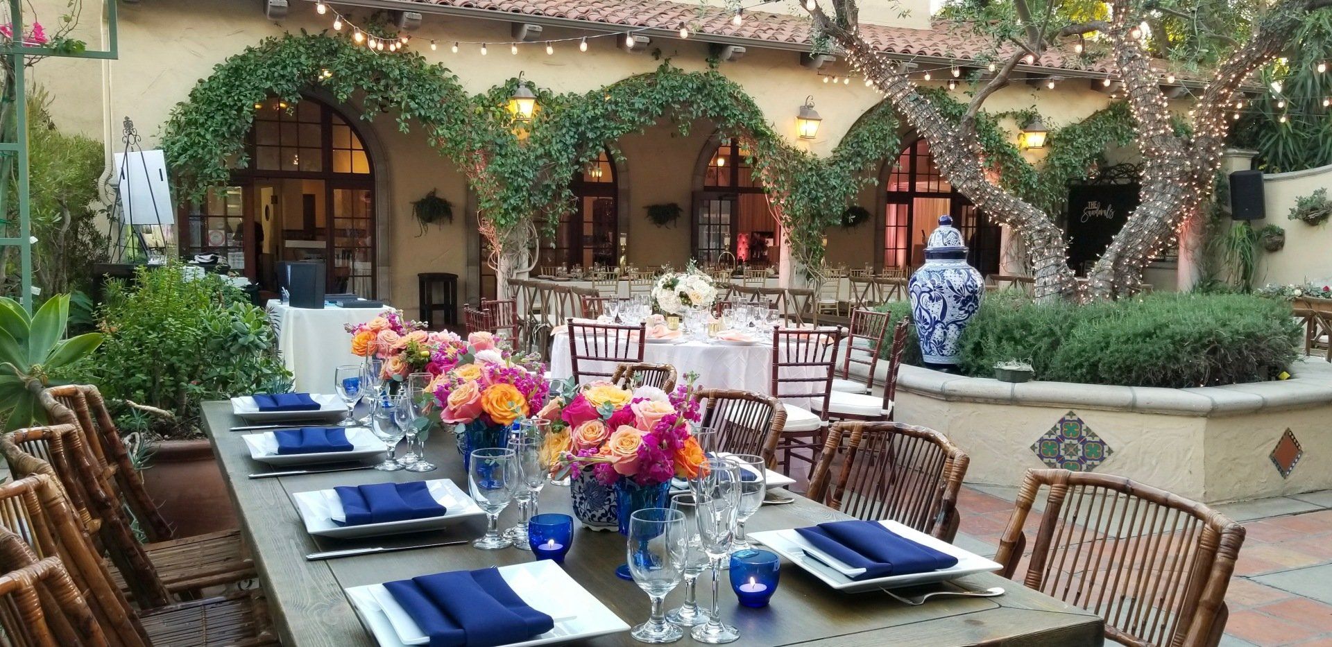 A long table with plates , glasses and flowers on it
