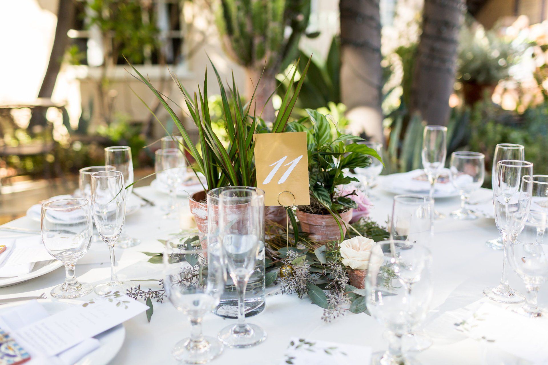 A table set for a wedding reception with plates , glasses , flowers and a table number.