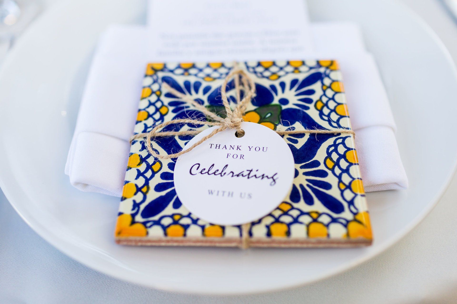 A thank you card is sitting on a white plate next to a napkin.