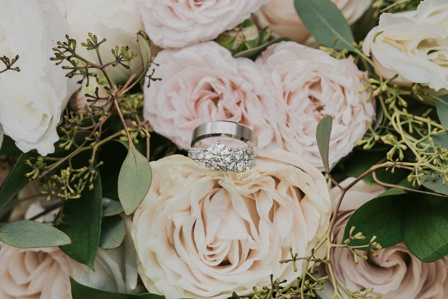 A couple of wedding rings sitting on top of a bouquet of flowers.
