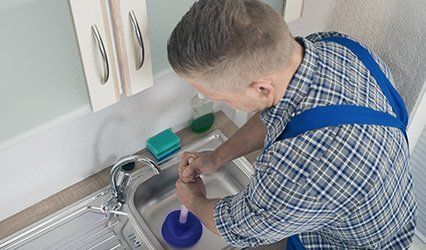 Worker Pressing Plunger In Sink - Power Rodding Sewer Opened in Hammond, IN