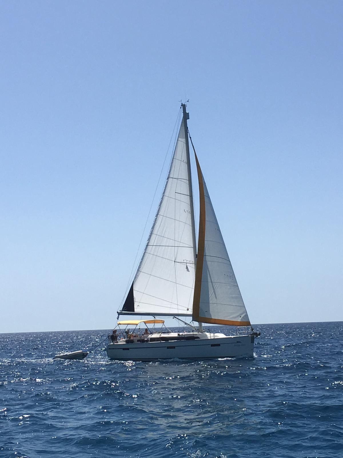 White sailboat on choppy blue water under a clear sky
