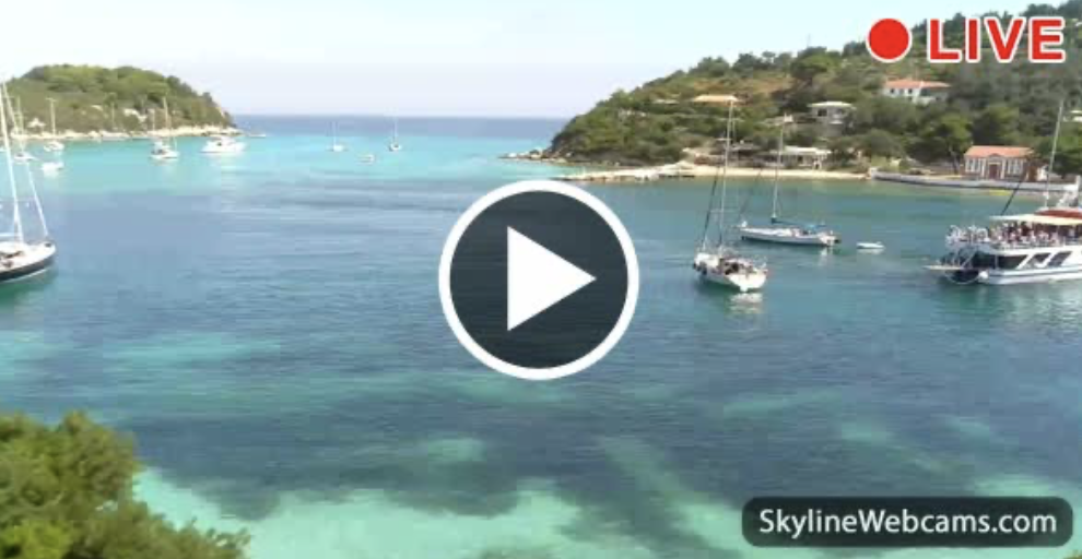 Webcam Lakka Live webcam view of a turquoise bay with boats, green islands, and a play button overlay