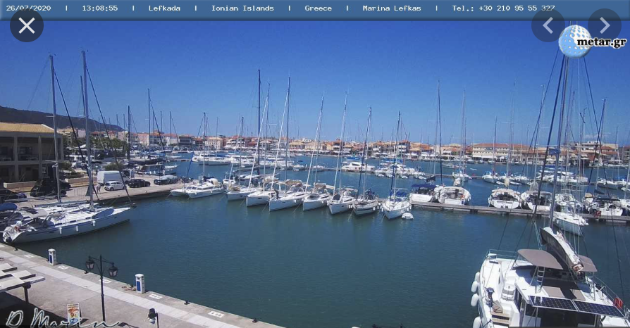 Webcams Lefkas Marina filled with white sailboats on calm blue water under a clear sky