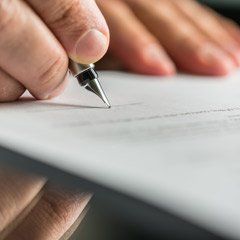 A person is writing on a piece of paper with a pen.