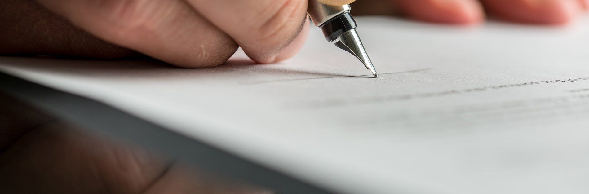 A person is writing on a piece of paper with a fountain pen.