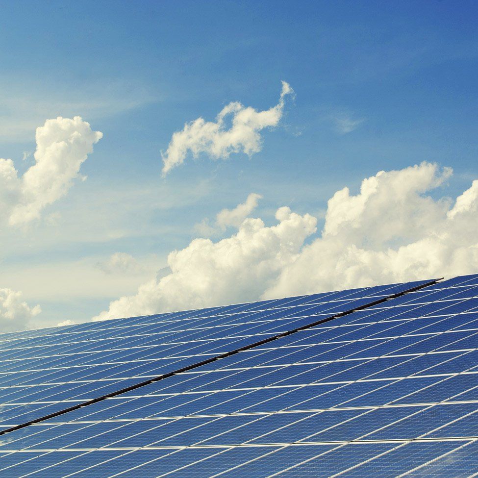A row of solar panels against a blue sky with clouds