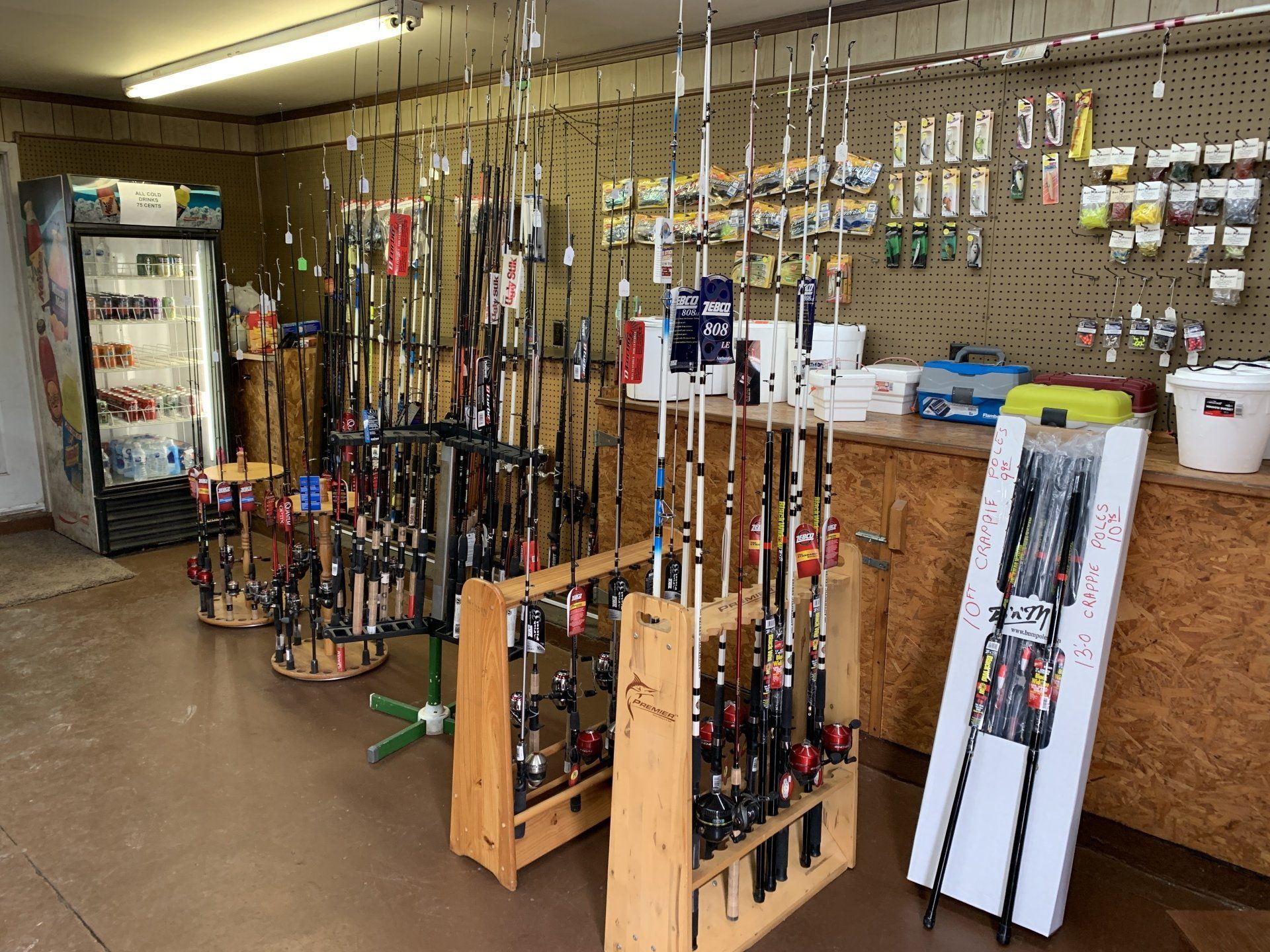 Inside a fishing supply store, fishing rods displayed on wooden racks. Tackle and bait line the walls.