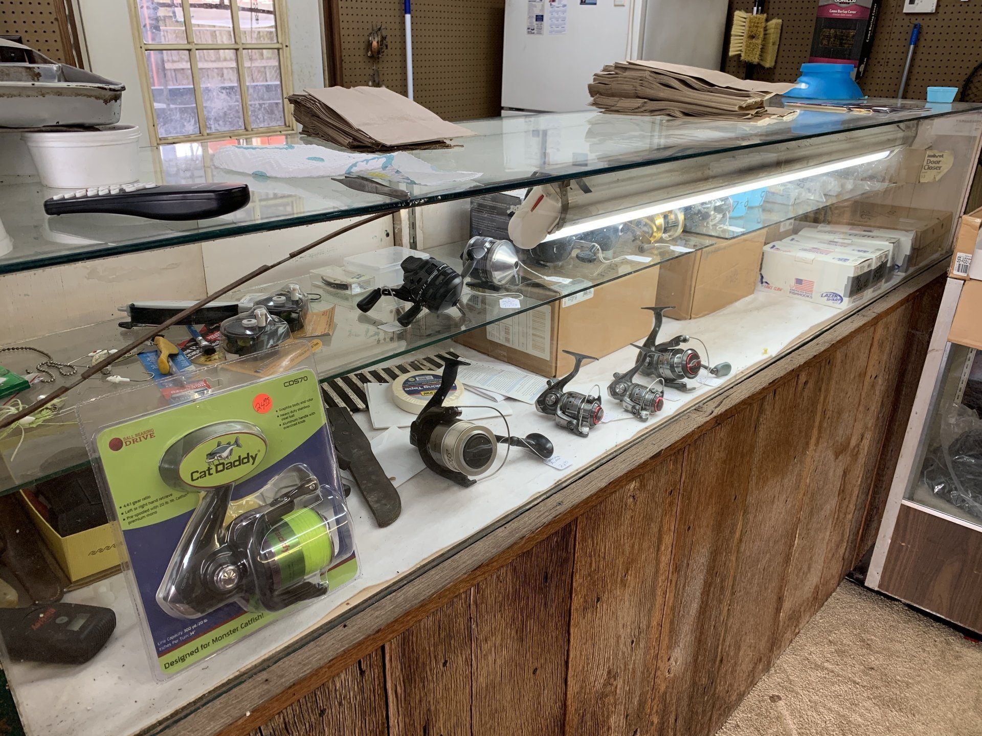 A glass display case with fishing reels for sale in a shop.