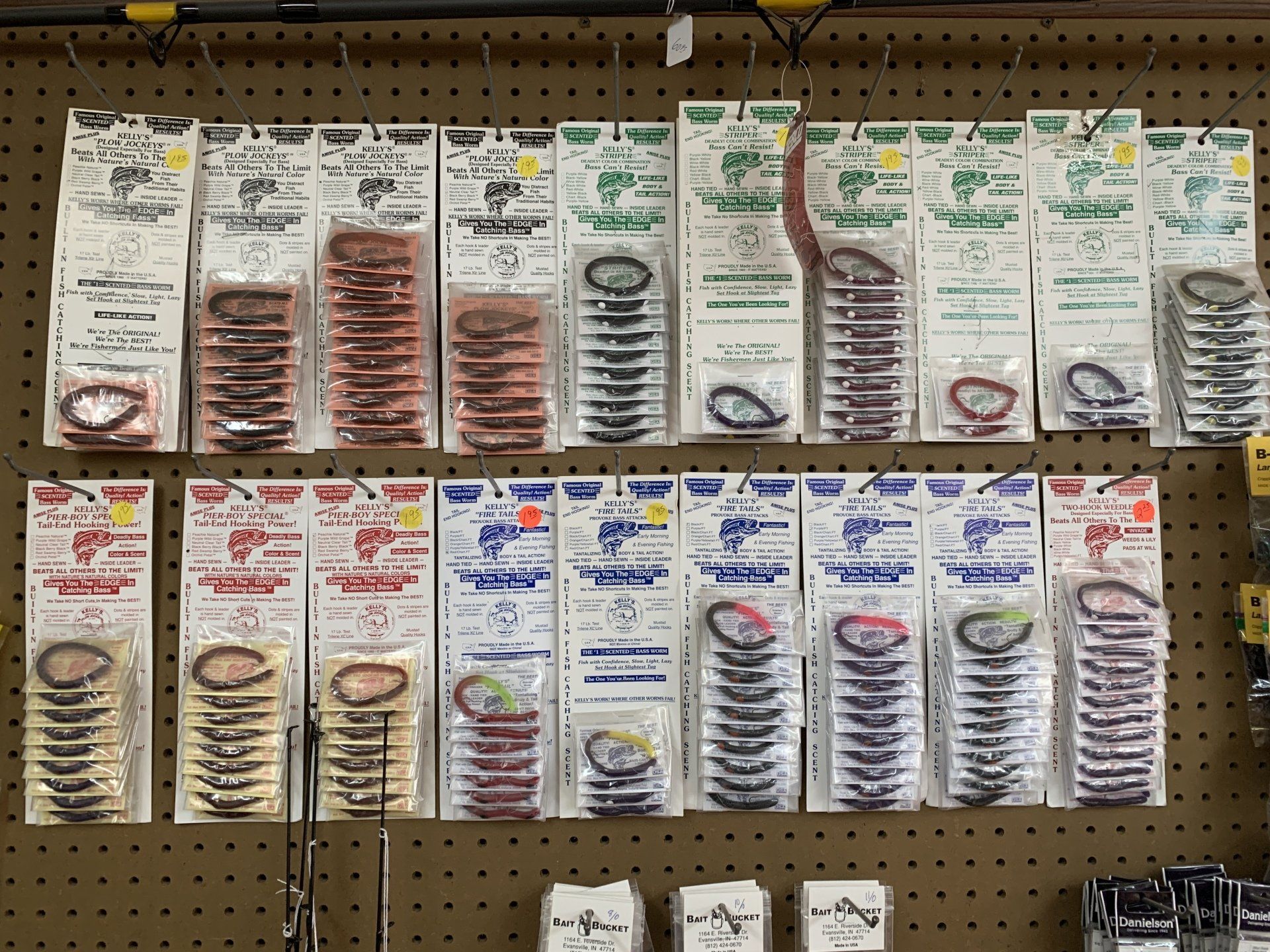 Rows of fishing lures on display at a store, various colors and styles in clear packaging.