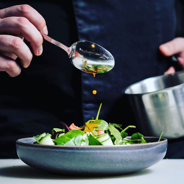 Eine Person hält einen Löffel über eine Schüssel Salat