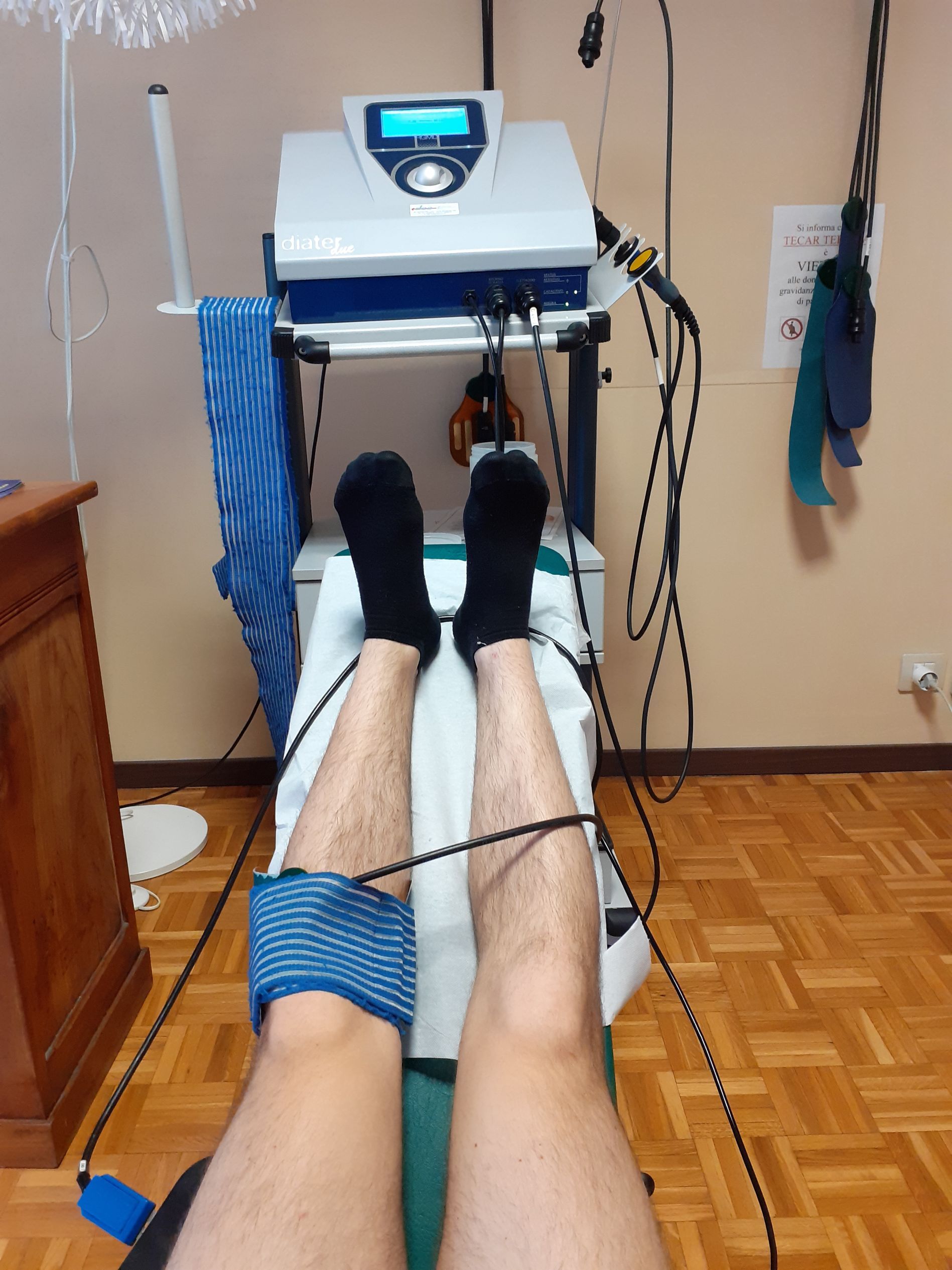 Persona sottoposta a elettroterapia per la gamba, con elettrodi e fili collegati.